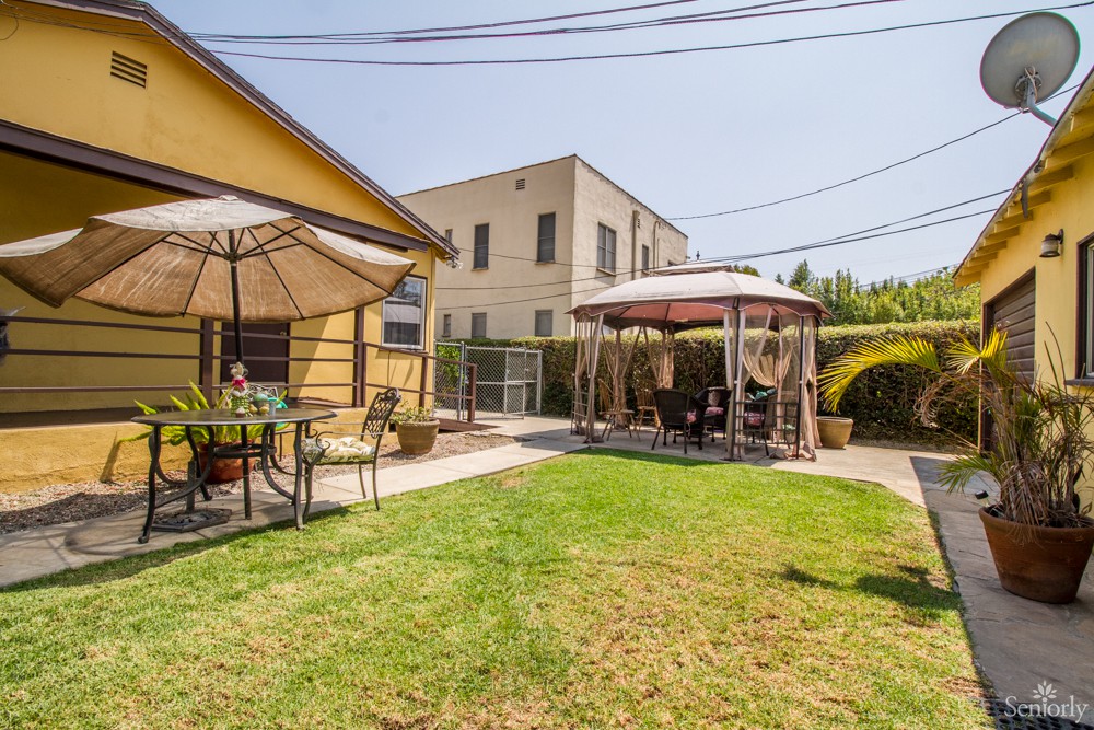 A sunny backyard with a patio set and gazebo.