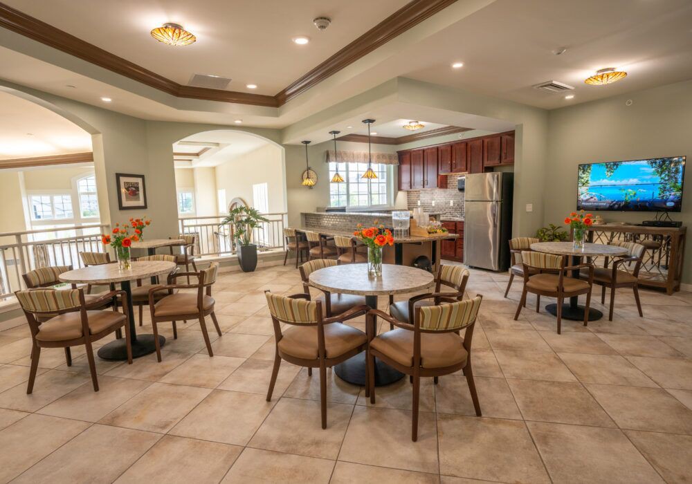 A cozy dining area with several tables and chairs, adjacent to a modern kitchen.