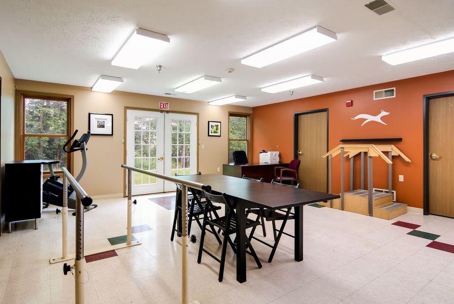 A rehabilitation room equipped with exercise equipment and parallel bars for physical therapy.