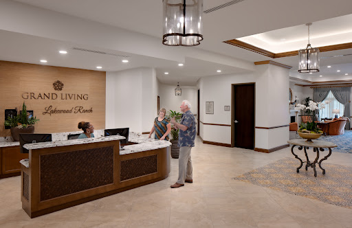 A warm and inviting reception area with a modern design, featuring a front desk and visitors engaging with staff.