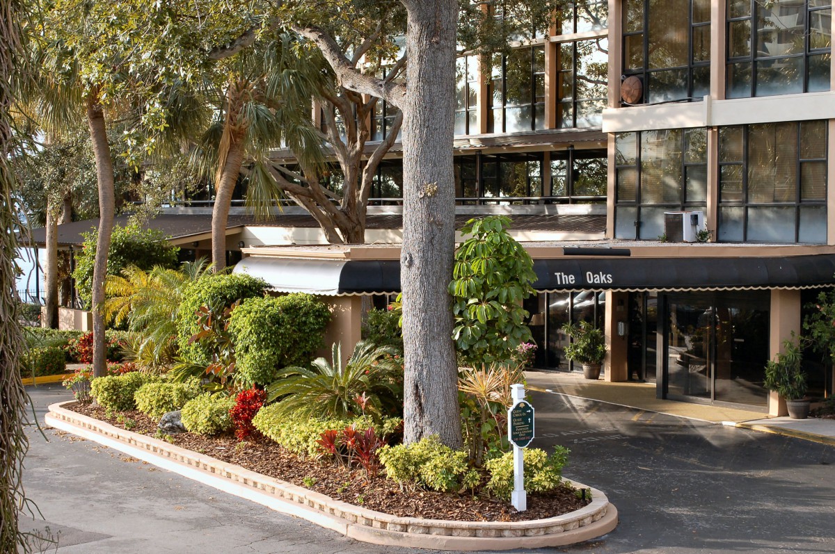 A hotel entrance surrounded by lush landscaping and trees.