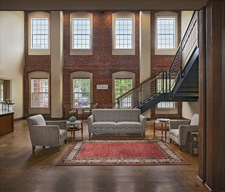 Spacious loft with high ceilings, featuring a cozy seating area and a modern staircase.