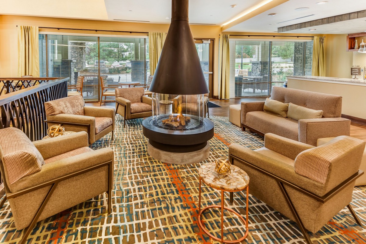 A modern and cozy living room with a central fireplace and comfortable seating.