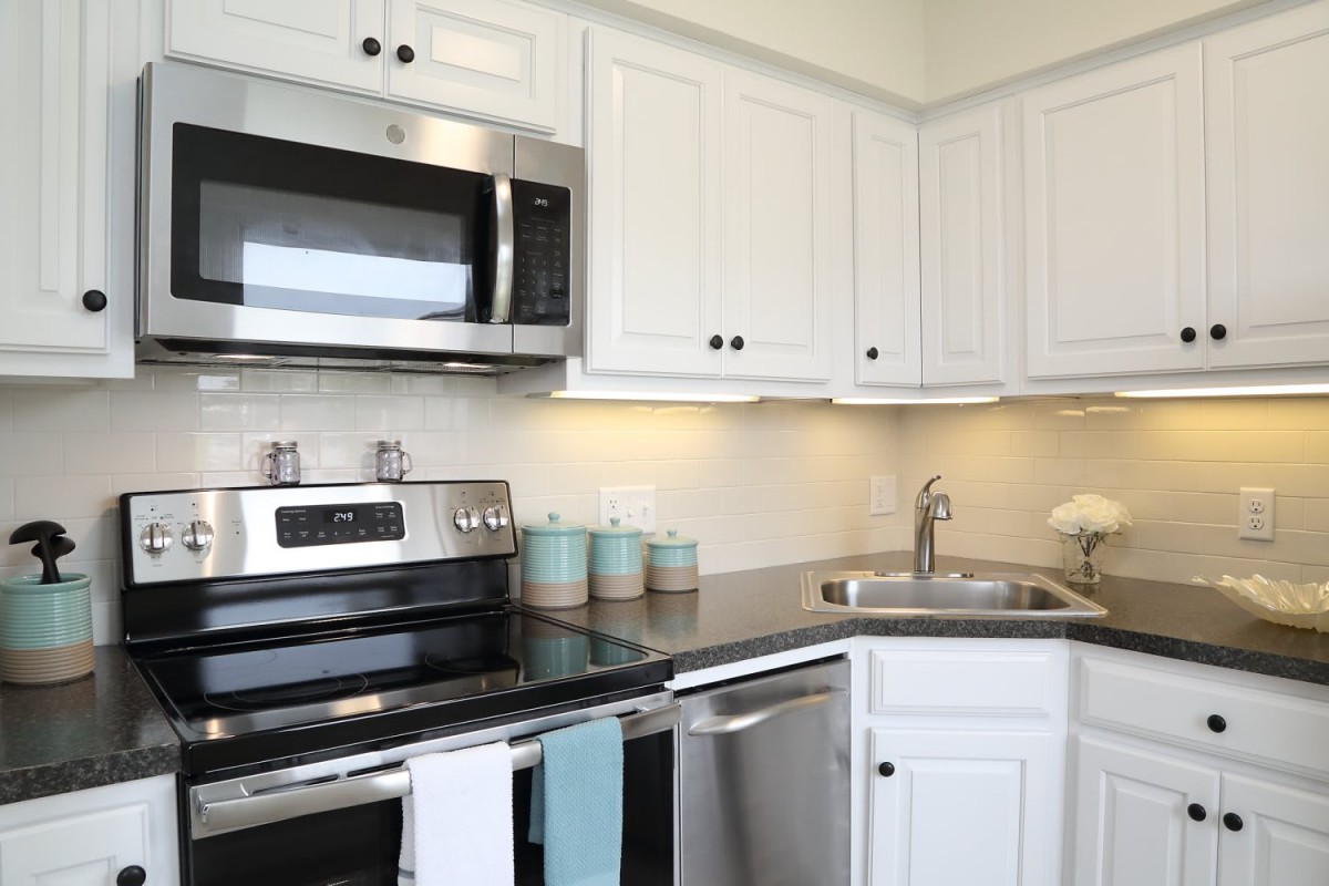 A modern kitchen with white cabinets and stainless steel appliances.