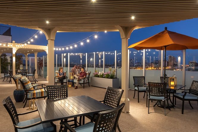 A cozy outdoor patio with string lights illuminating the evening ambiance, featuring tables and chairs for relaxation.