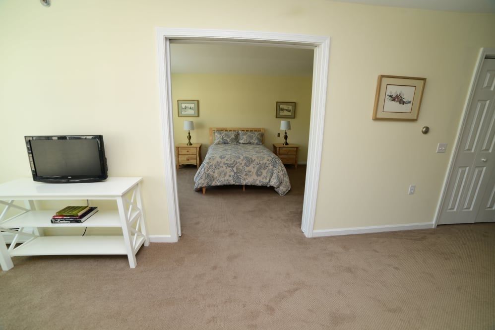 A cozy bedroom with a double bed, nightstands, and a small TV in an adjacent room.