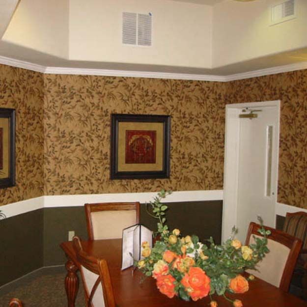 A well-decorated dining room with floral arrangements and framed artwork on the walls.