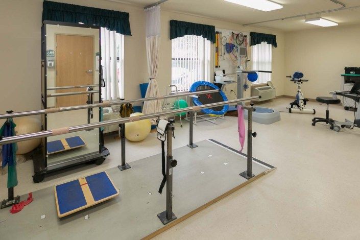 A physical therapy room equipped with various rehabilitation tools and parallel bars.