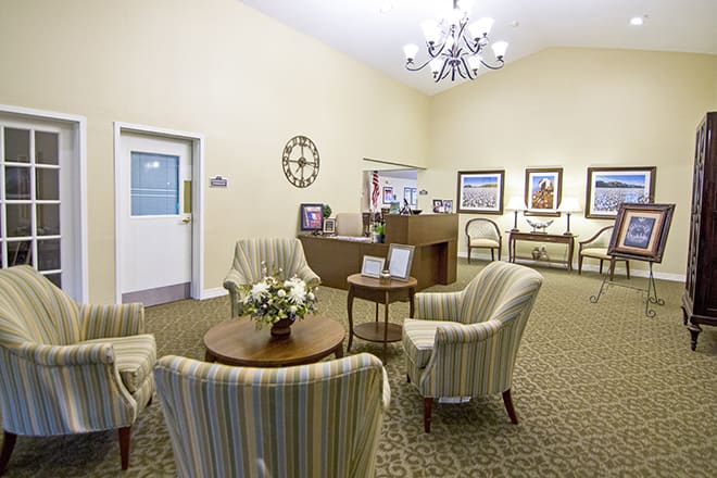 A cozy reception area with chairs and a small table, decorated with a clock and artwork.