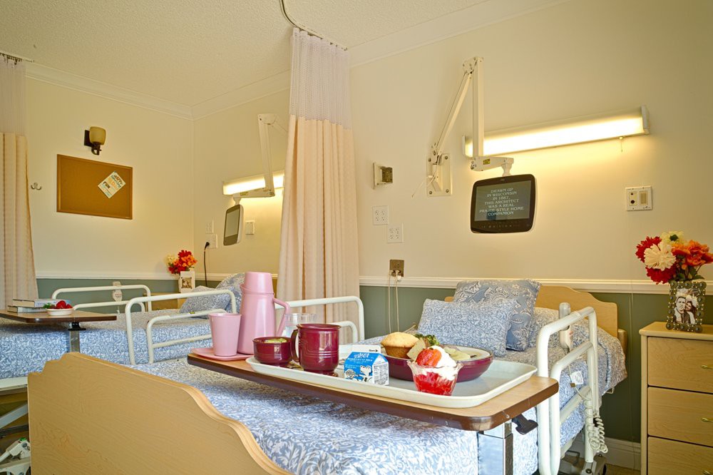 A hospital room with a patient bed and a meal tray.