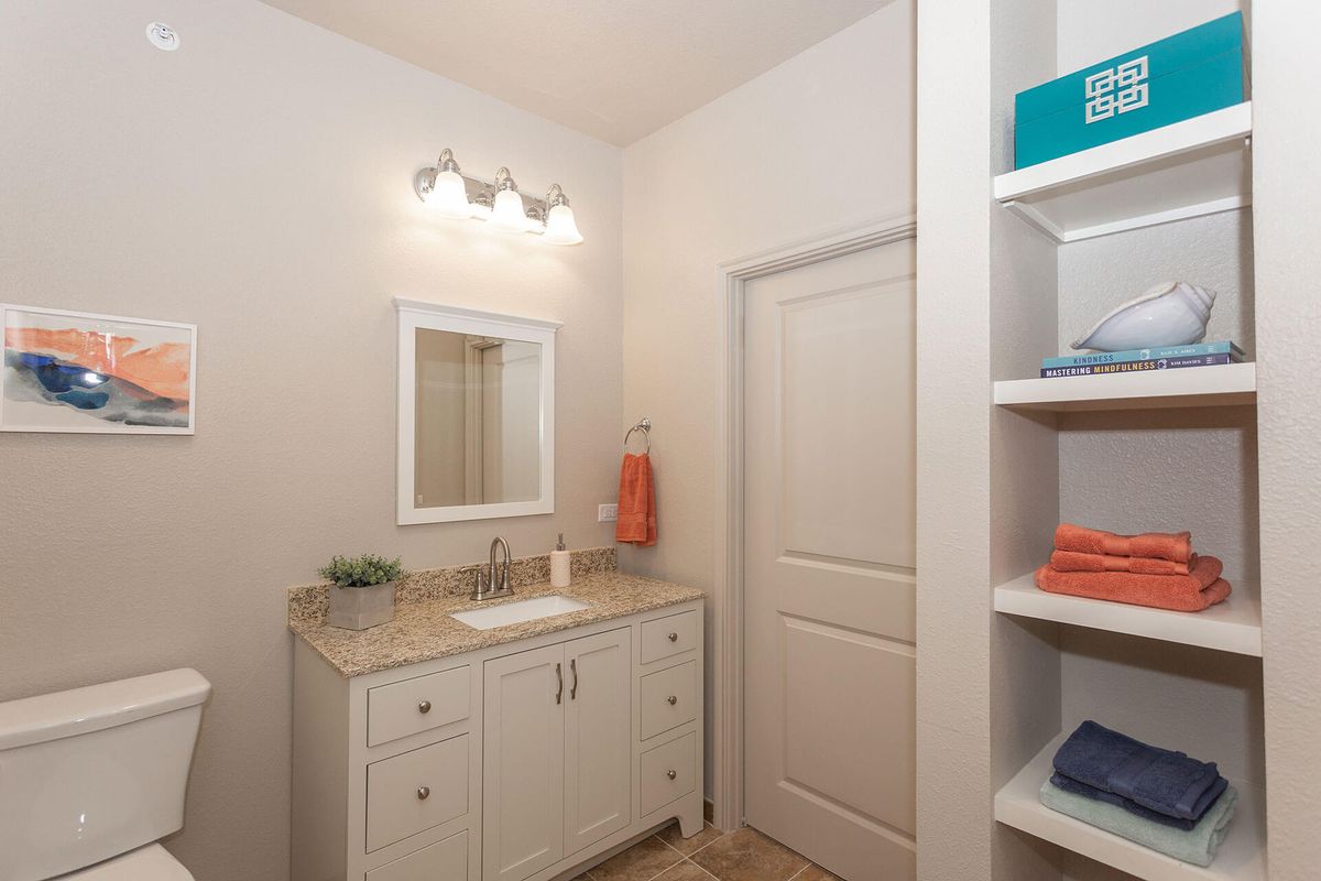 A neatly organized bathroom with a vanity, sink, and towel storage.