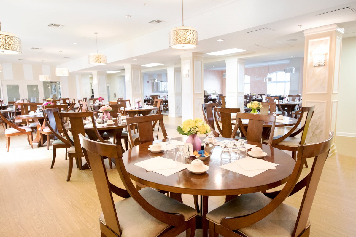 A spacious and elegantly decorated dining area with wooden tables and chairs, beautifully set for guests.
