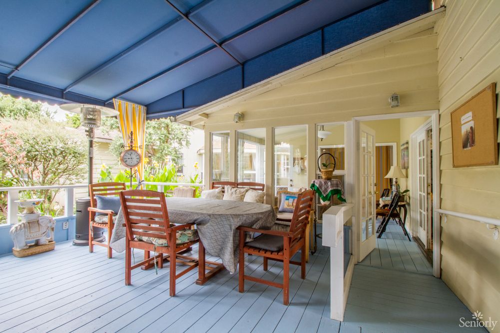 A cozy outdoor patio with a dining area featuring wooden furniture and a blue canopy.
