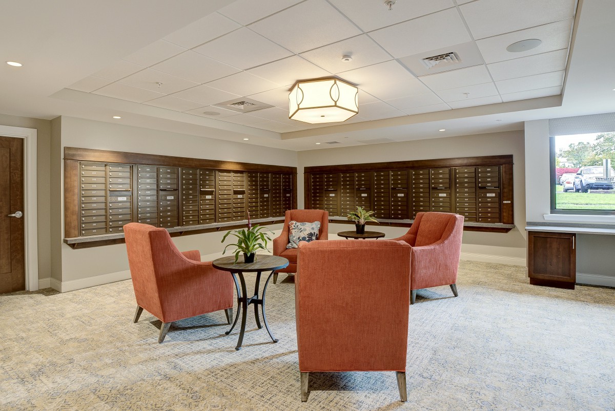 A spacious lobby with comfortable seating, decorative plants, and a wall of mailboxes.