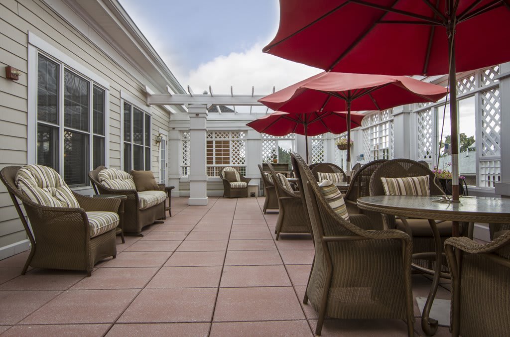 A spacious outdoor patio with wicker furniture and red umbrellas.
