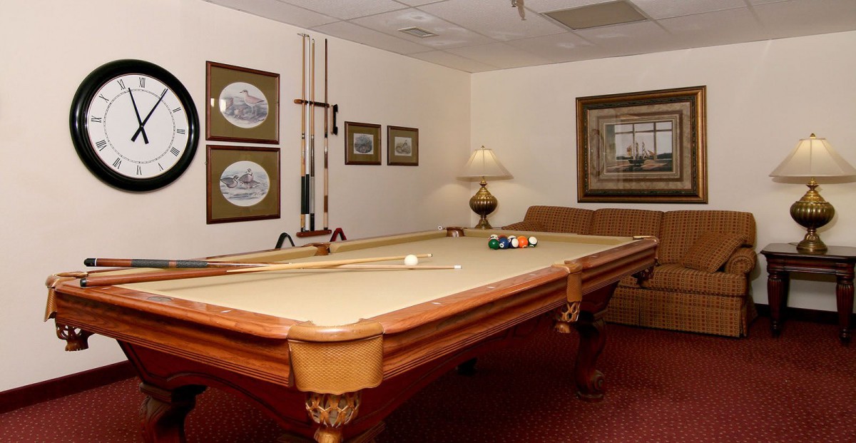 A cozy game room featuring a classic billiards table, surrounded by artwork and ambient lighting.