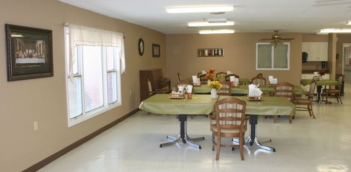 A neatly arranged dining room with multiple tables and chairs, featuring simple decor and ample lighting.