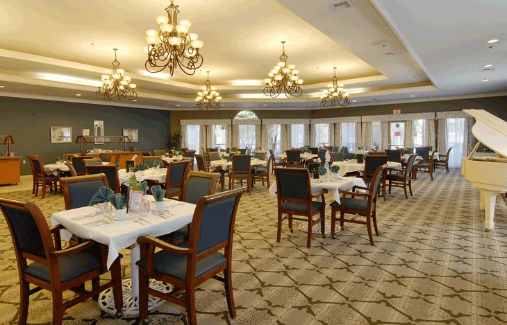 An elegant dining room with chandeliers and neatly arranged tables.