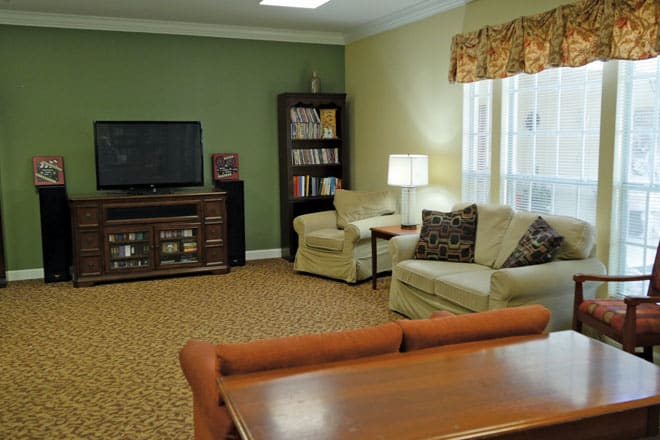 A cozy living room with a television, bookshelf, and comfortable seating.