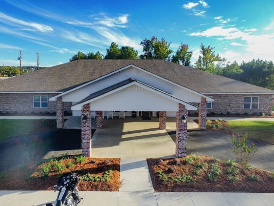 A well-maintained building entrance with a landscaped pathway under a clear blue sky.