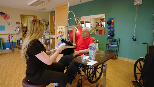 A therapist assists an elderly patient in a rehabilitation session.