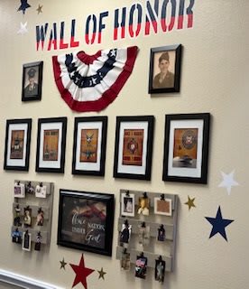 A Wall of Honor displaying framed photographs and memorabilia recognizing military veterans.