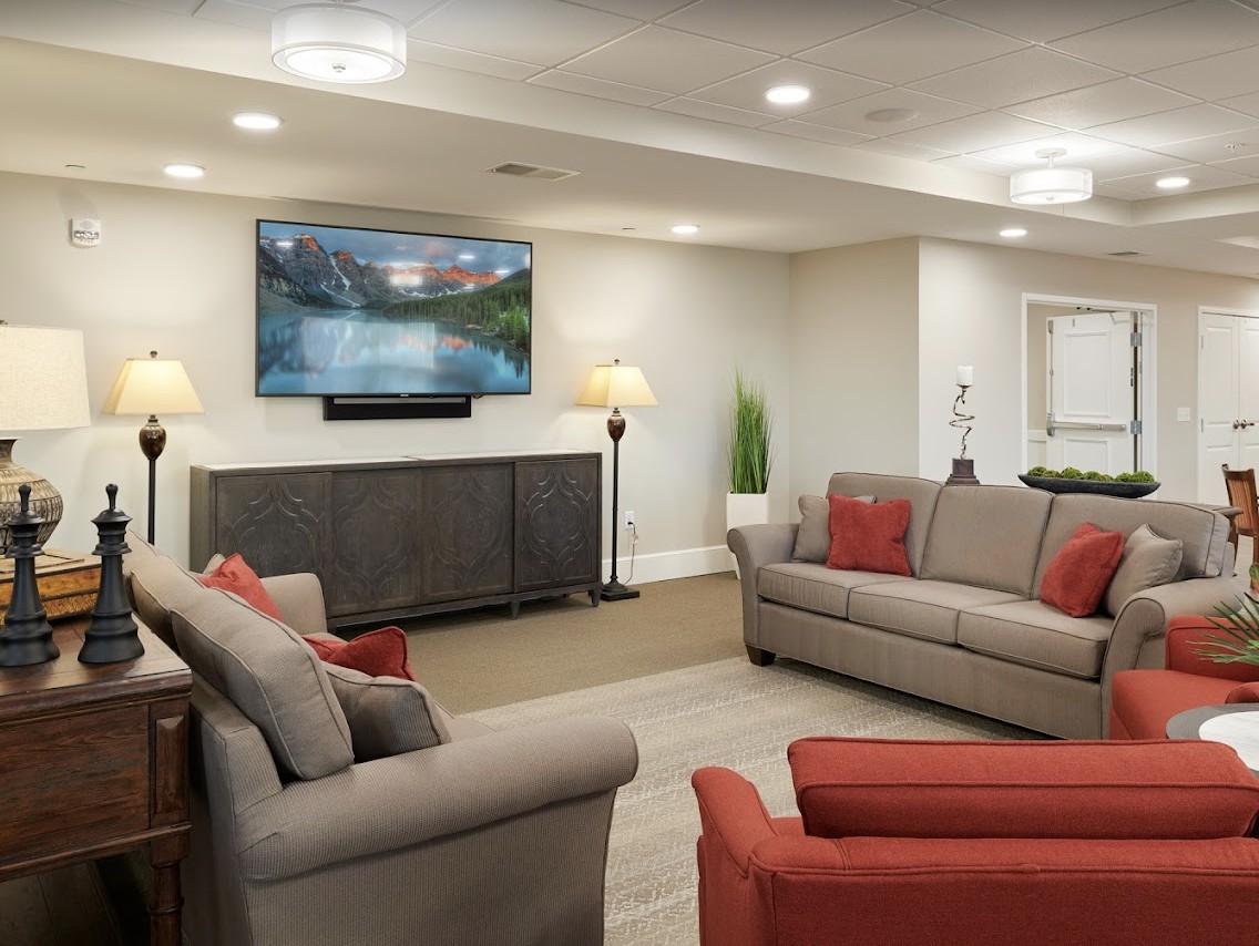 A modern living room with cozy sofas, a mounted television, and warm lighting.