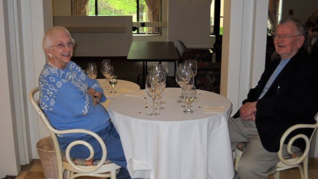 Two people sitting at a restaurant table with wine glasses.
