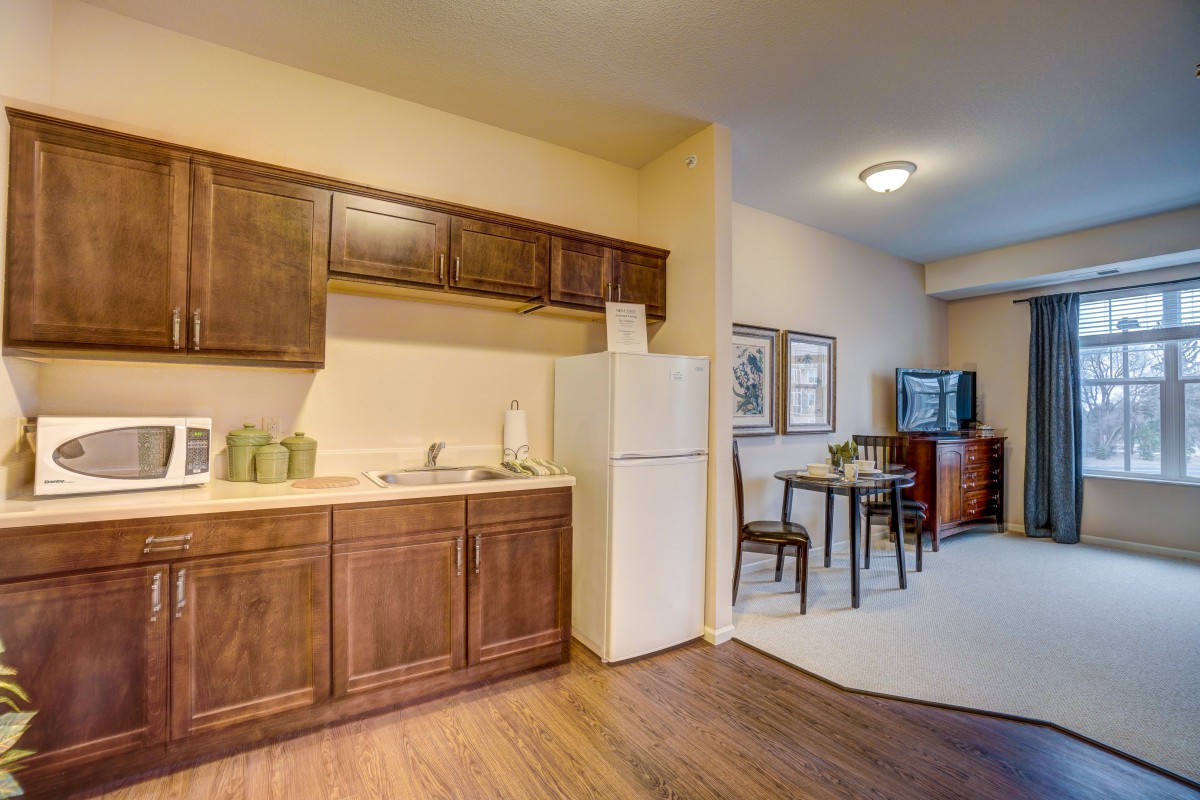 A cozy apartment kitchen with wooden cabinets and a small dining area.