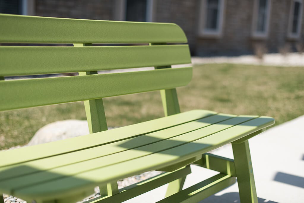A green wooden bench in a sunny outdoor setting.
