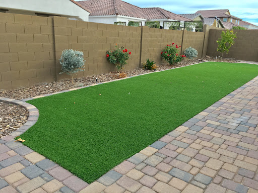 A well-maintained backyard featuring artificial grass and a paved patio.