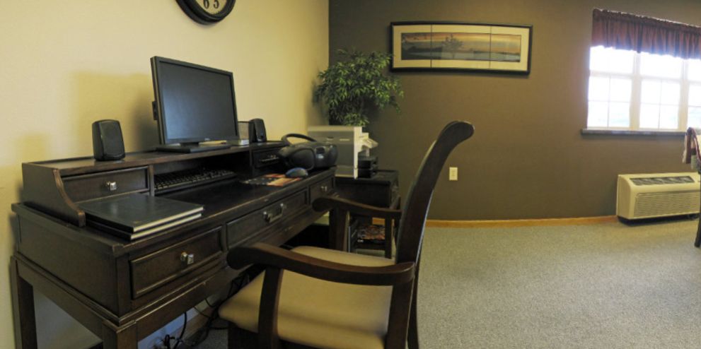 A tidy office workspace featuring a desk with a computer, chair, and decorative items.