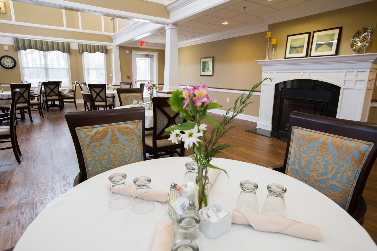 A cozy dining room with elegantly set tables and a fireplace.