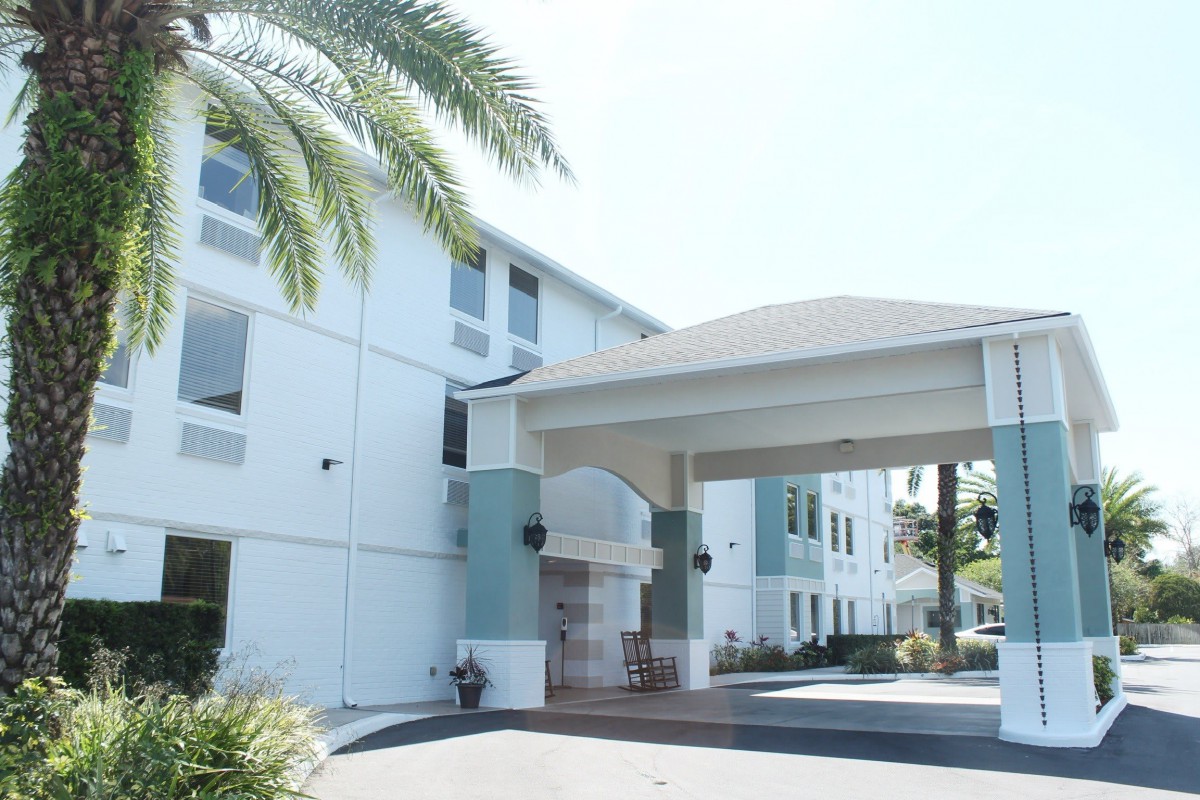 The entrance of a modern hotel with palm trees and an inviting facade.