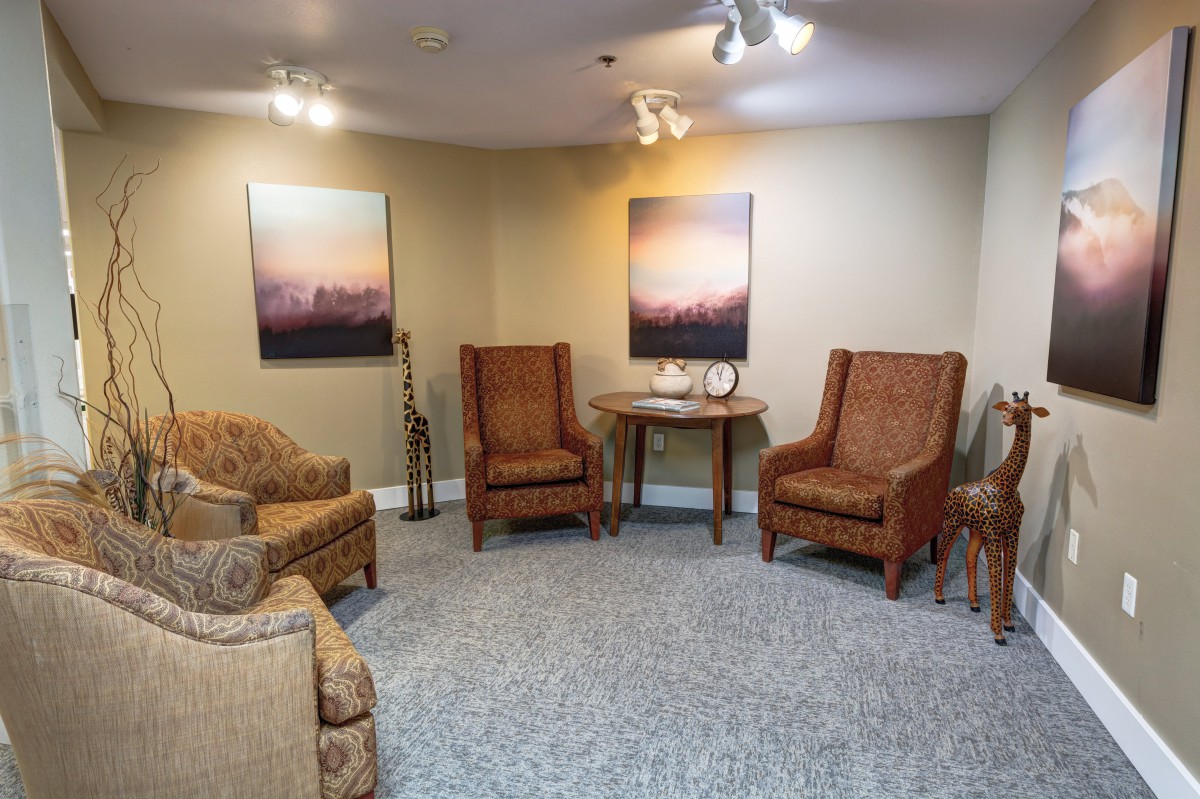 A cozy living room setup with multiple chairs, a small table, and artwork on the walls.