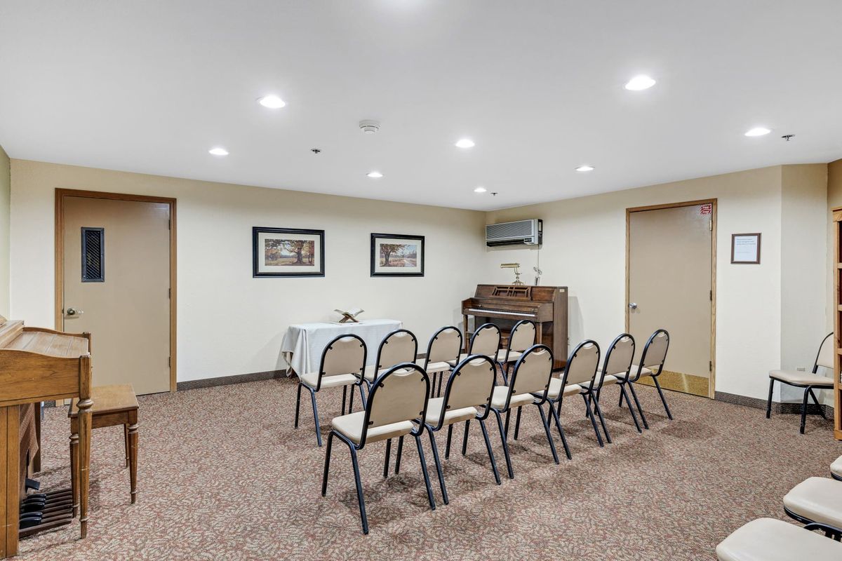 A small conference room arranged with chairs facing a table and a projector screen.
