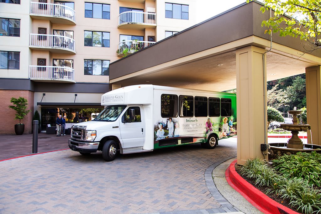 A shuttle bus parked under a building entrance.