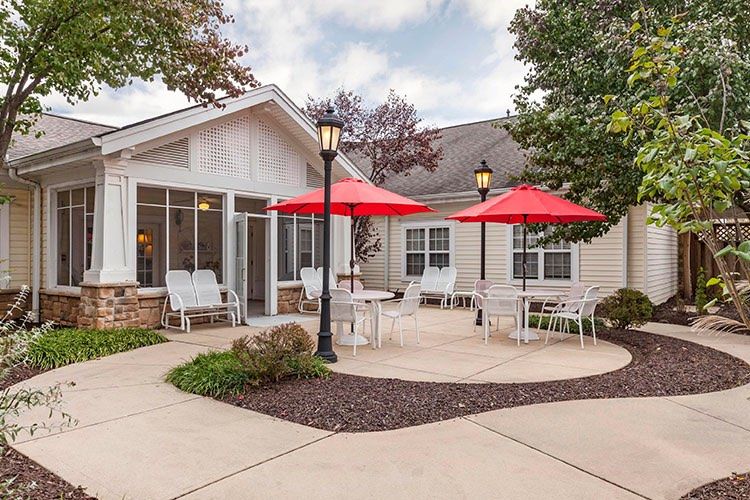 A cozy residential patio with red umbrellas and outdoor seating.