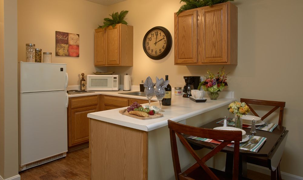 A cozy kitchen with wooden cabinets, white countertops, and various appliances including a microwave and coffee maker.