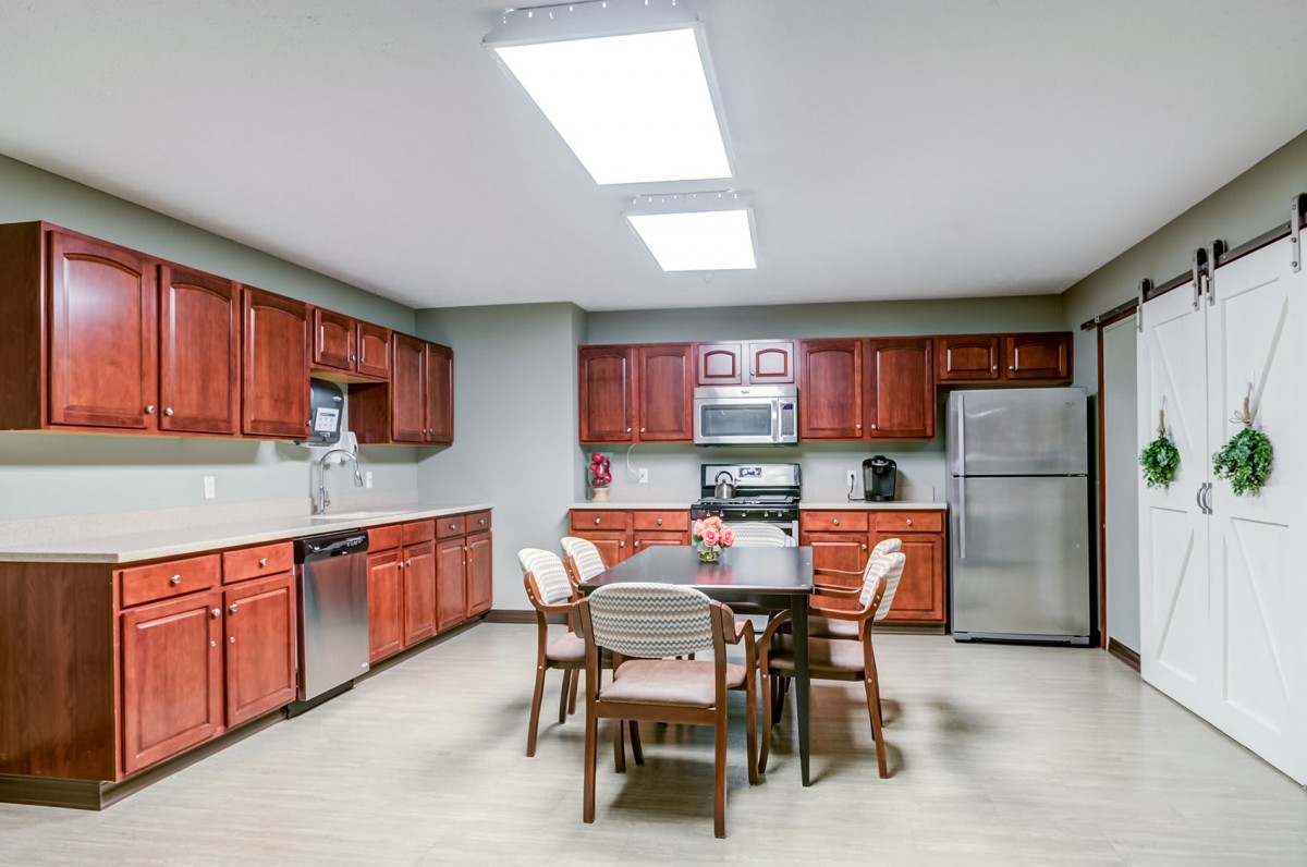 A modern kitchen with wooden cabinets, stainless steel appliances, and a dining table with chairs.