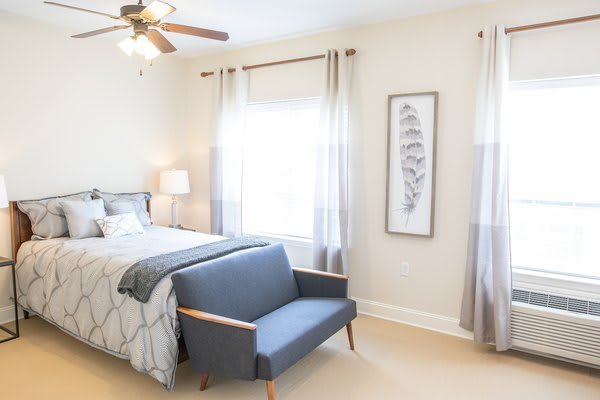 A bright and modern bedroom with a cozy bed, stylish sofa, and ample natural light.