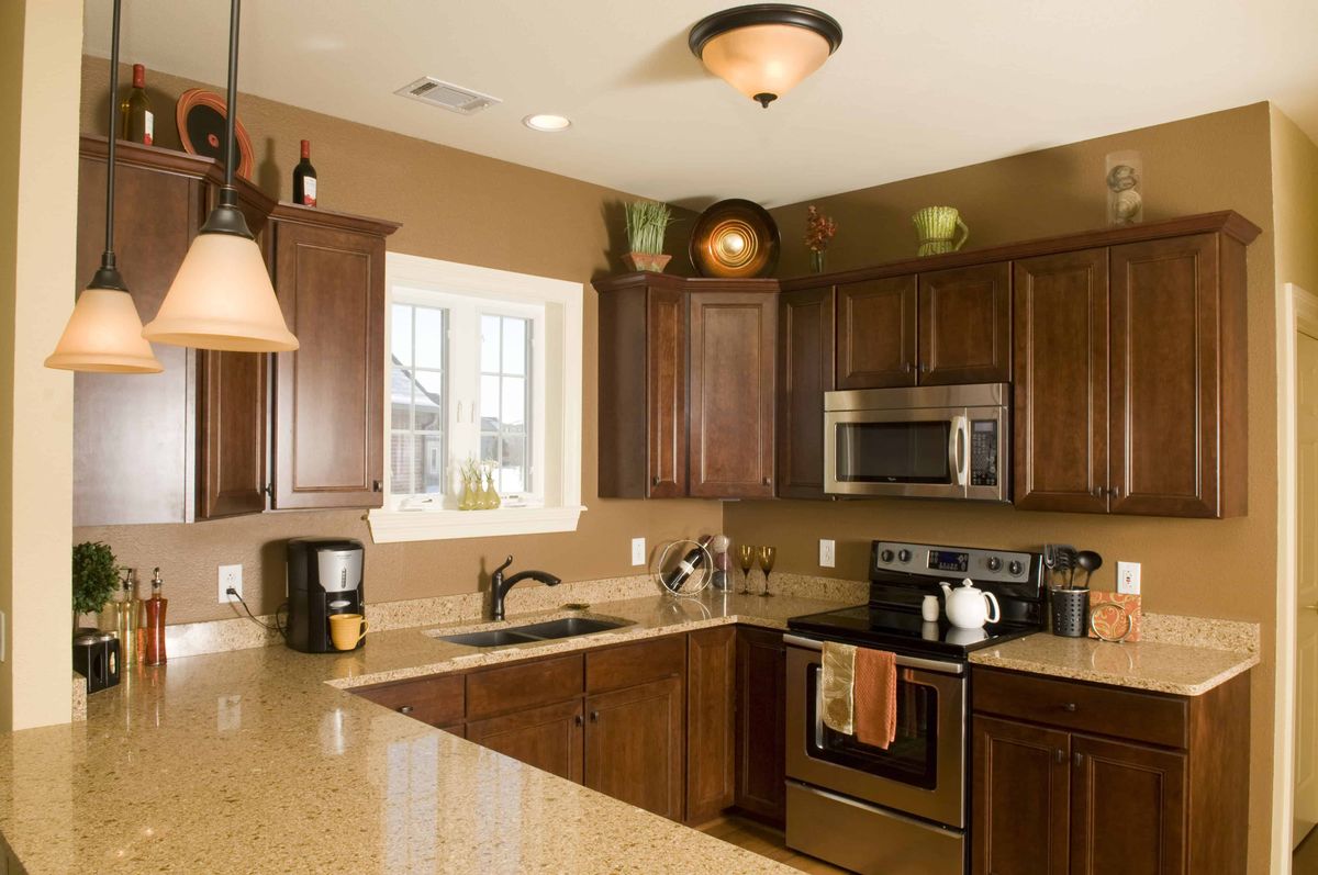 A modern kitchen with dark wood cabinets and stainless steel appliances.