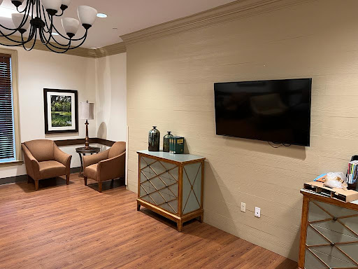 A cozy living room area featuring comfortable chairs, a wall-mounted TV, and stylish furniture.
