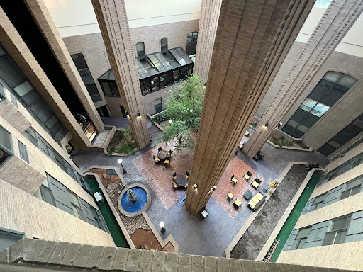 A view of a contemporary indoor courtyard featuring a fountain surrounded by seating areas and greenery.