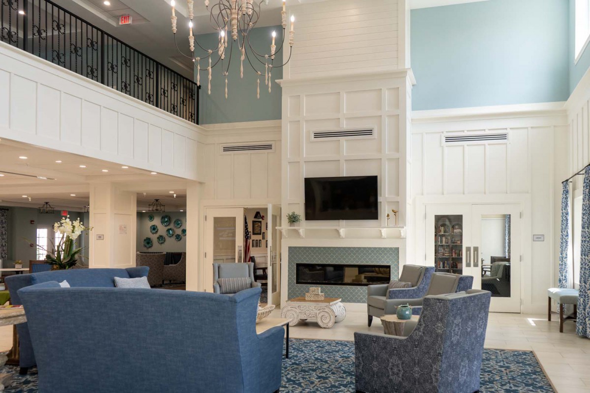 A modern living room with elegant furnishings, featuring a grand chandelier and a cozy fireplace.