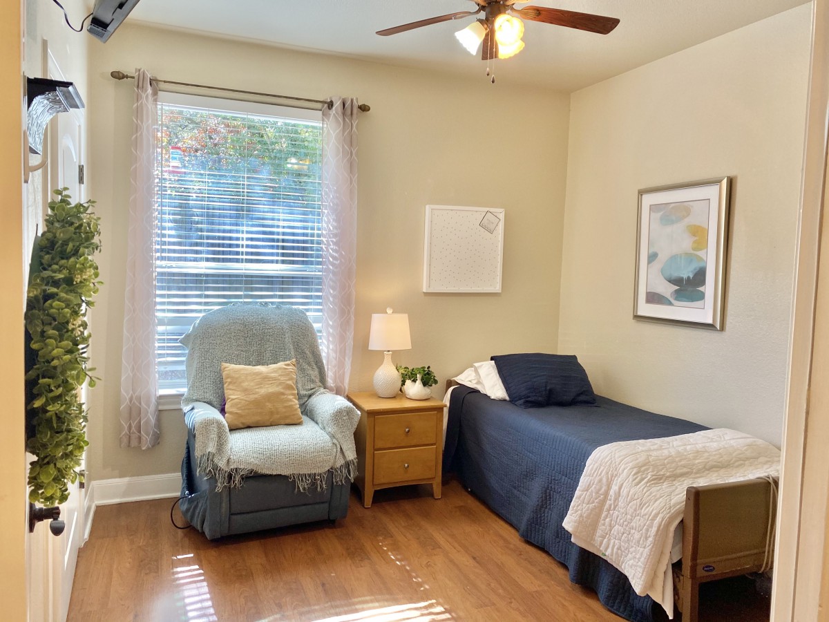 A cozy bedroom with a single bed, armchair, and soft lighting.
