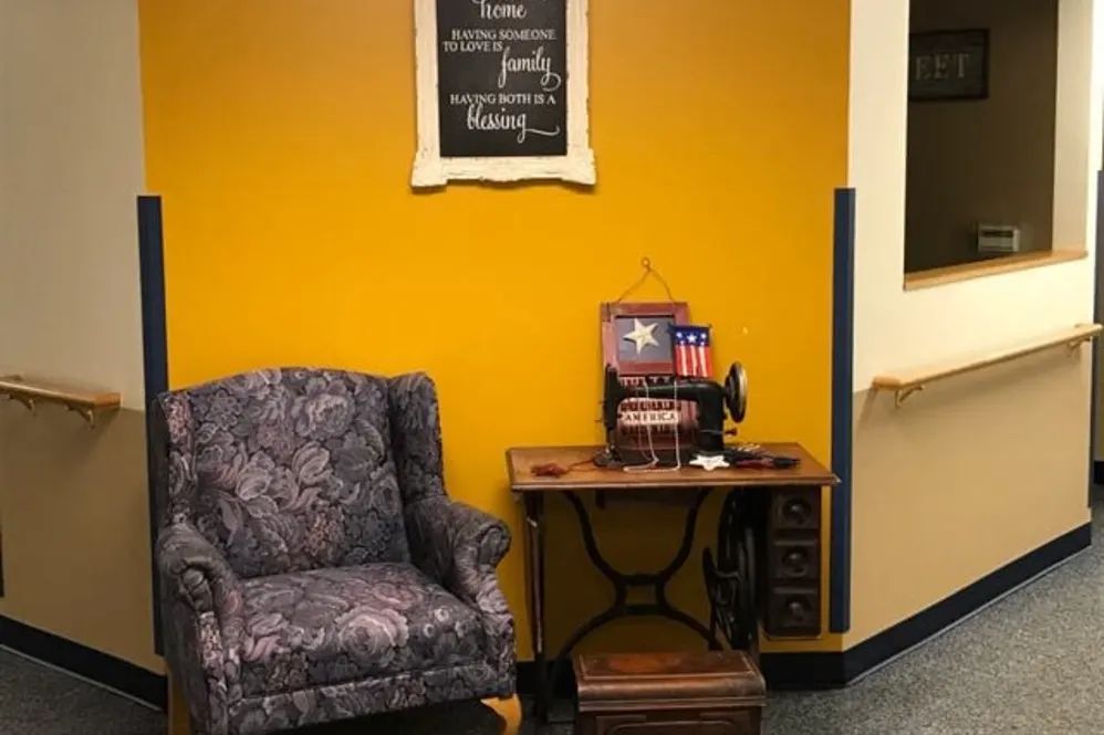 A cozy corner featuring a vintage sewing machine and armchair with decorative wall art.