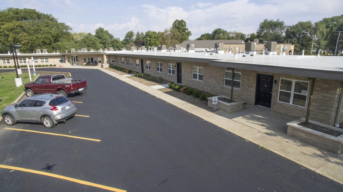 A view of a motel with an adjacent parking lot on a clear day.