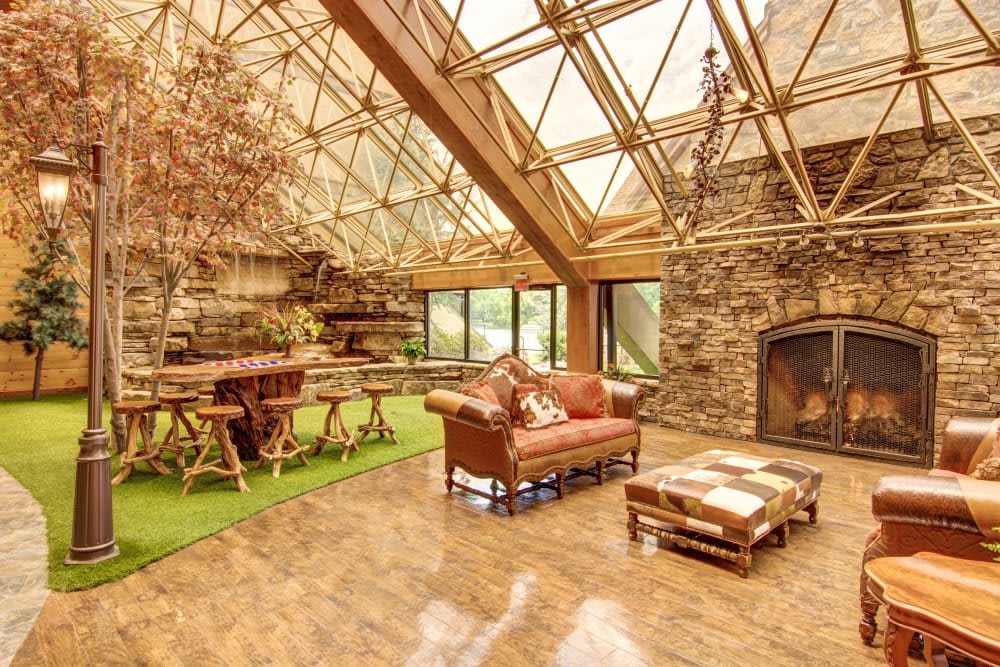 A rustic living room with a glass ceiling, stone fireplace, and comfortable furniture.