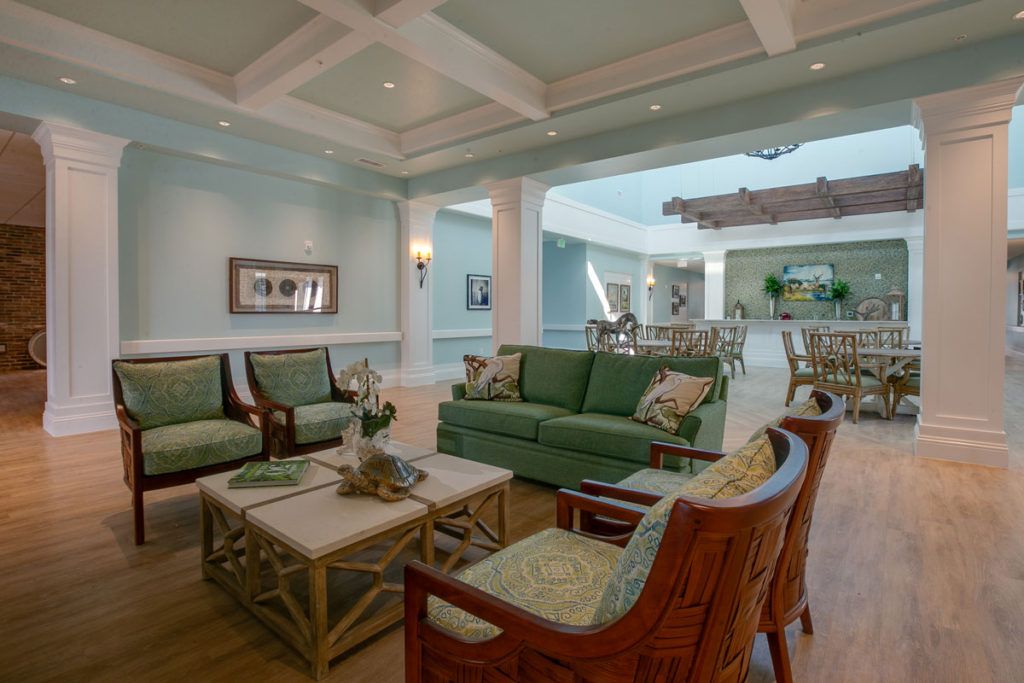 A spacious living room with green couches and a wooden coffee table, featuring elegant interior design elements.